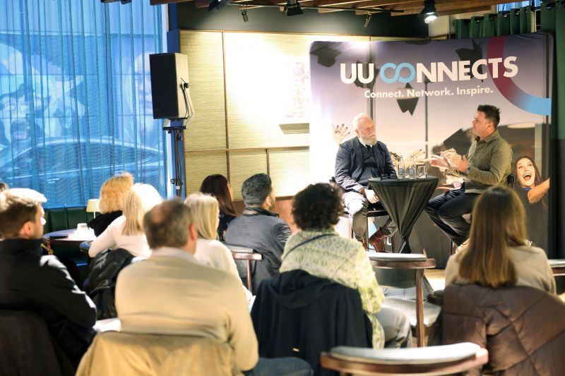 - A crowd POV picture showing Pete Snodden talk to Professor Paul Moore with previous UU Graduates listening in 