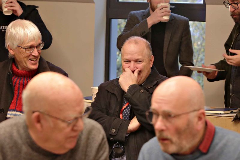 A group of men engaged in conversation while seated around a table