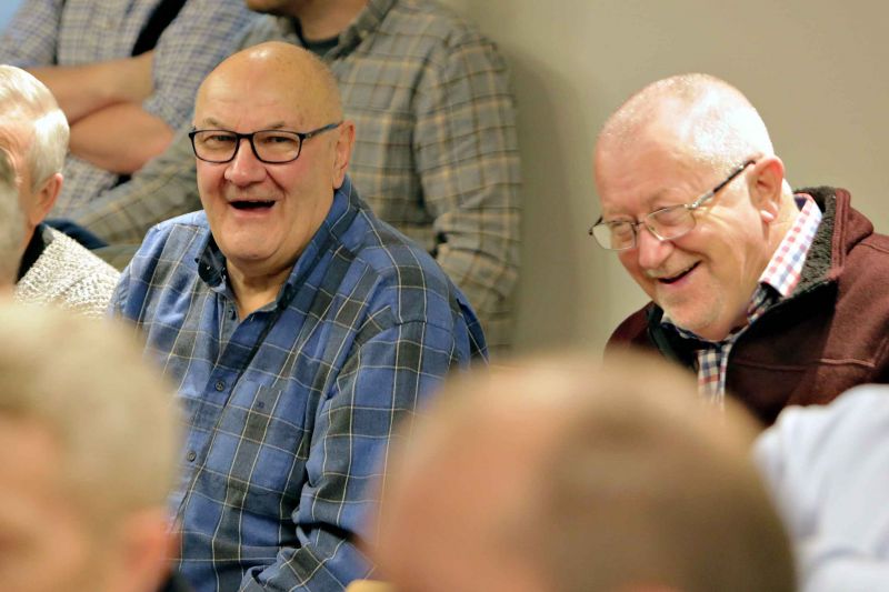 Two elderly men in a room, enjoying each other\'s company and laughing heartily