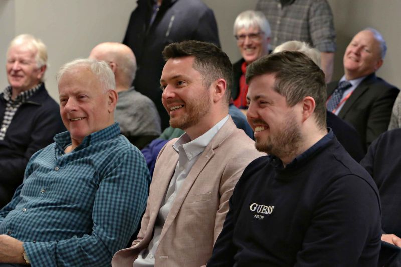 A group of men seated together in a room, engaged in conversation