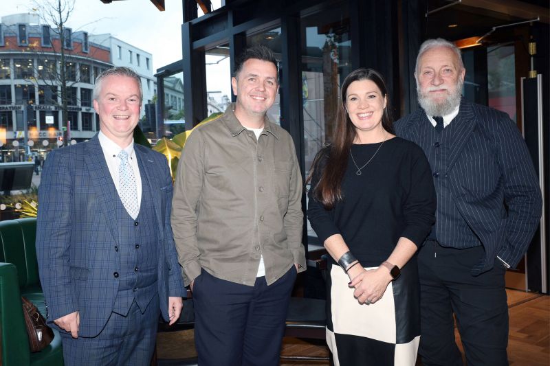 Malachy Ó Néill, Pete Snodden, Kathy Marrow and Professor Paul Moore taking a picture in front of a green booth in the Academy Restaurant in Belfast