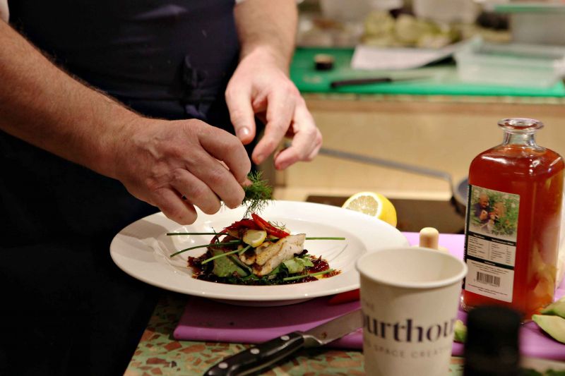 A man skilfully arranges food on a plate, showcasing his culinary preparation and attention to detail 